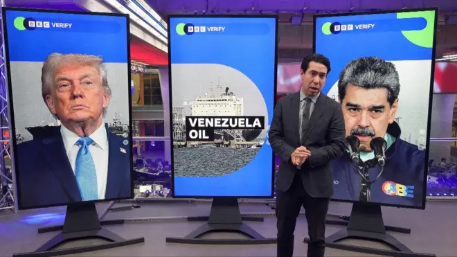 「VENEZUELA OIL」の文字と、トランプ氏とマドゥロ氏の写真が表示された3枚のディスプレイの前に立つBBC記者