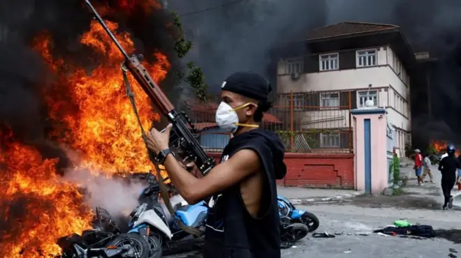 भदौ २४ गतेको दिन लुटिएका प्रहरीको हतियार बोकेर प्रदर्शनमा सहभागी भइरहेका एक युवा। 