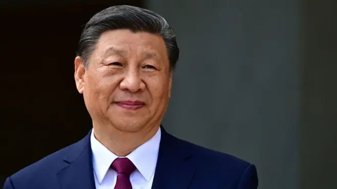 Xi Jinping yambaye ikote. Araraba muri 'camera'. 