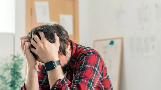 Homem sentado com as mãos apoiadas na cabeça