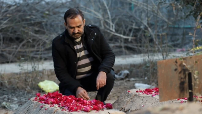 ผู้ชายนั่งหน้าหลุมศพ