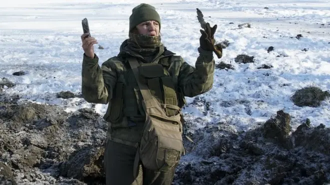 Украинская военнослужащая показывает кусок шрапнели, вынутый из воронки, оставшейся после взрыва в Авдеевке. 31 января 2017 года