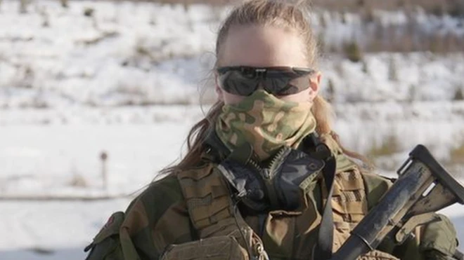 सन ग्लास, मास्क, पूरी वर्दी और बंदूक से लैस महिला सैनिक