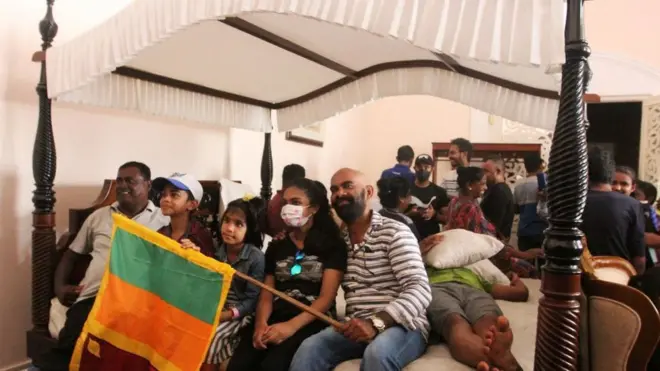 People sit on a four-poster bed inside the Sri Lankan president's official residence on Sunday