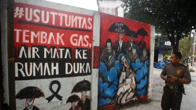 Seorang warga Kota Malang melewati mural menuntut pengusutan tuntas Tragedi Kanjuruhan di Malang, Rabu, 5 Oktober 2022.