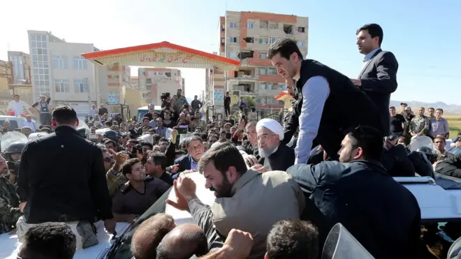 President Rouhani visited Sarpol-e Zahab on Tuesday - the buildings behind him highlight the difference in damage between privately-built and state-built homes
