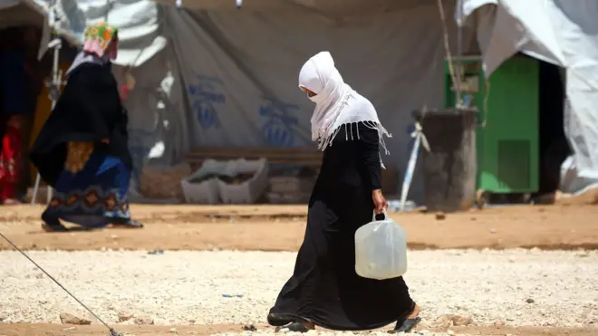 Pengungsi perempuan Suriah membawa air di kamp al-Mabrouka di desa Ras al-Ain di perbatasan Turki-Suriah.