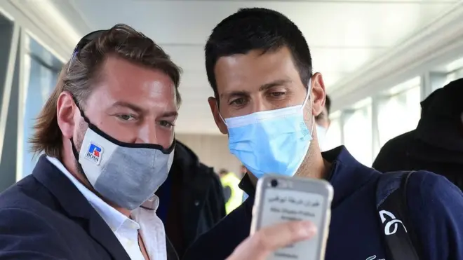 A man takes a selfie with Novak Djokovic as they leave a plane