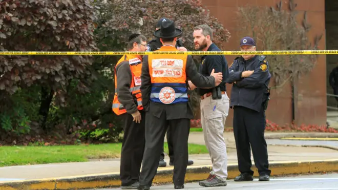 Police officers guarding the Tree of Life synagogue following shooting at the synagogue, speak with men in orange vest from a Jewish burial society in Pittsburgh, Pennsylvania