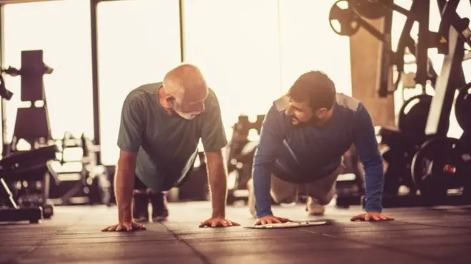 Personal trainer working exercise with senior man at gym.