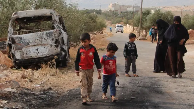 Syrian women and children gather at the site of a US raid near the Syrian village of Barisha (27 October 2019)