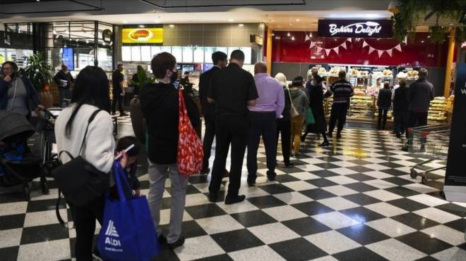 Customers stand in long lines at a check out counter at a bakery in the Woden area in Canberra, Australian Capital Territory, Australia
