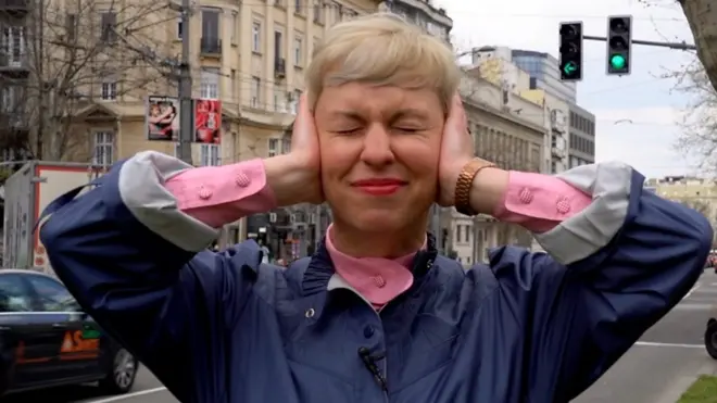 BBC novinarka na ulici Beograda prikriva uši rukama