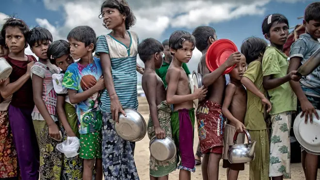 Children holding bowls queuing for food