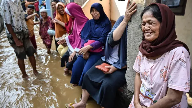 Residents react as they take shelter amid floodwaters in Jakarta on April 26, 2019