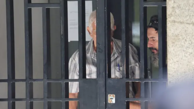 الرجل المشتبه به يفسح المجال لمسن بمغادرة المصرف.