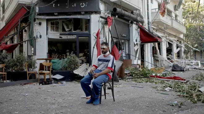Un hombre se sienta frente a un restaurante destruido por la explosion el 5 de agosto de 2020.