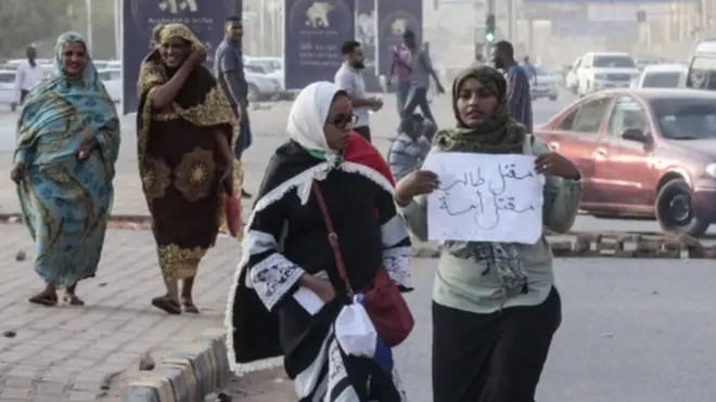 متظاهرتان في الخرطوم تحمل إحداهما لافتة كُتب عليها عبارة تقول "مقتل طالب مقتل أمة".