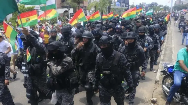Santa Cruz şehrinde geri çekilen polis memurları Bolivya bayrağını sallıyor