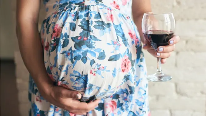 Femme enceinte tenant un verre de vin