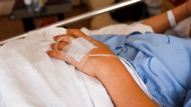 Paciente em cama de hospital - foto focaliza a mão
