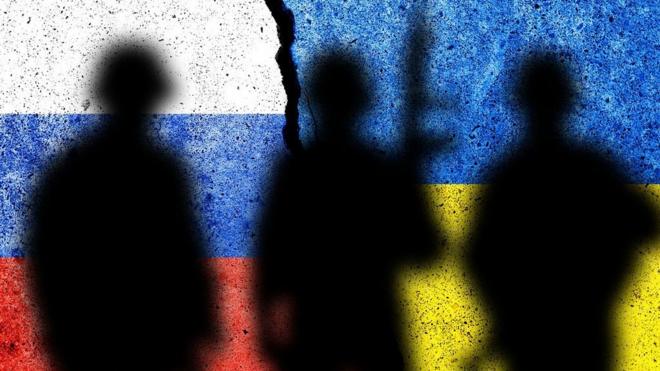 Sombras de soldados en muro con banderas de Ucrania y Rusia