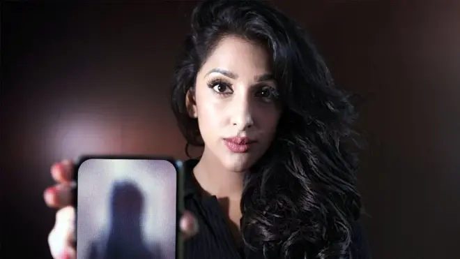 Panorama reporter Monika Plaha holding a photo with a pixellated image of a woman