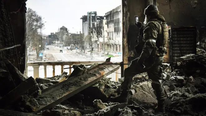 Un hombre toma una foto desde el teatro destrozado.