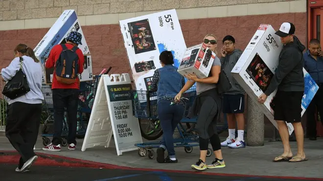 Compradores con grandes cajas de televisores.