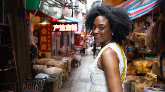 Jasmine walking down a street in China - markets around her