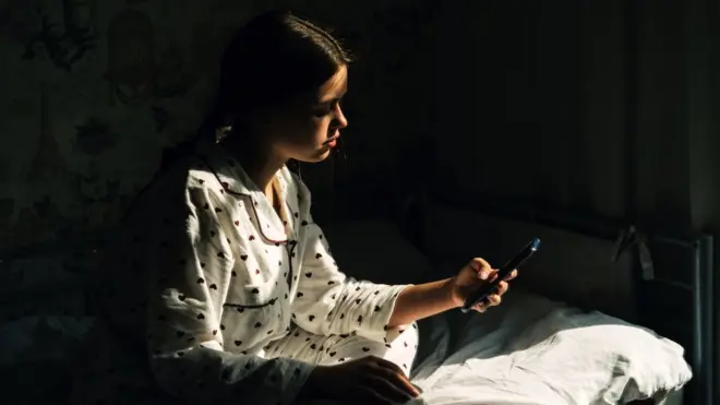 young woman on her phone in bed