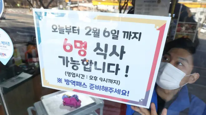 17일 대구 한 음식점 직원이 출입문에 '모임 6인·영업 9시' 거리두기 안내문을 붙이고 있다