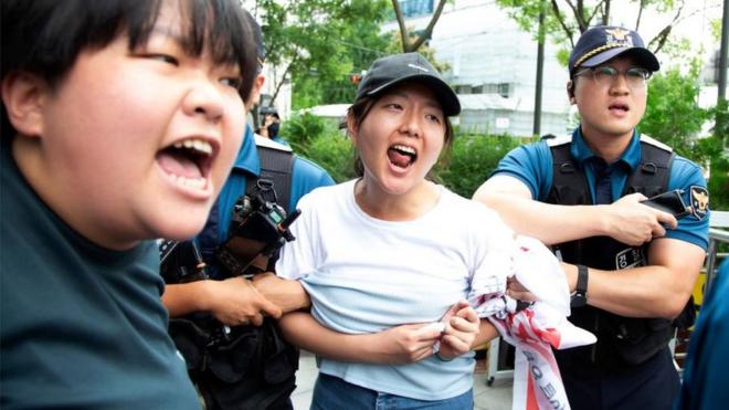 Police officials detain university student protesters as they try to enter the Japanese embassy amid a rally in Seoul, South Korea, 24 August 2023