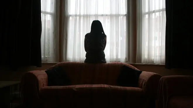 One young woman wey dey suffer from domestic violence for Asia stand near window for her house