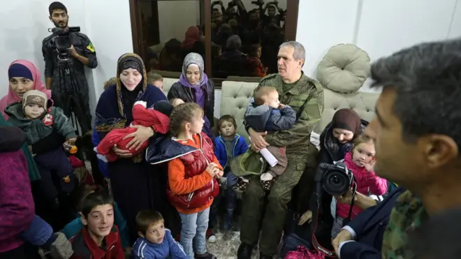 Ziyad Sabsabi menggendong seorang anak setelah unit perlindunag Kurdis menyerahkan perempian dan anak-anak asal Rusia di Qamishli, Suriah, pertengahan November 12.