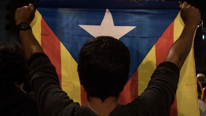 Un hombre de espaldas sostiene una bandera independentista catalana.