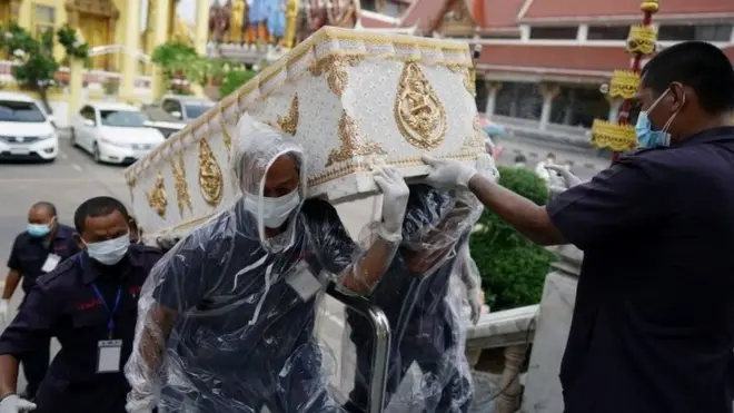 เจ้าหน้าที่ขนโลงศพผู้เสียชีวิตจากโควิด-19 ขึ้นเมรุที่วัดแห่งหนึ่งในกรุงเทพฯ เมื่อวันที่ 24 เม.ย.