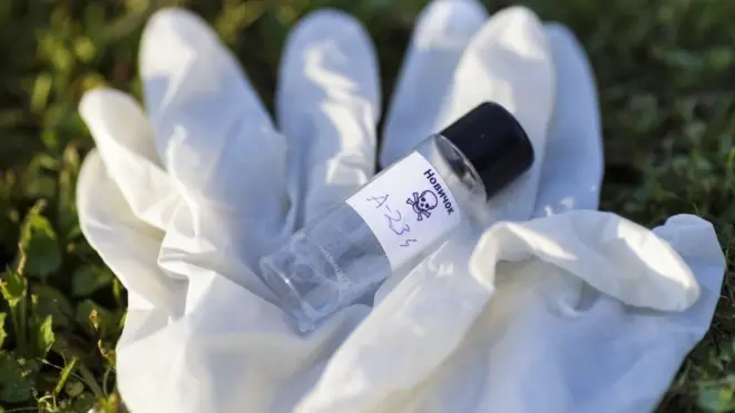 Illustration with mock up of Novichok agent (A-234) bottle and white rubber gloves on grass. Fictitious title on bottle in Russian: Novichok