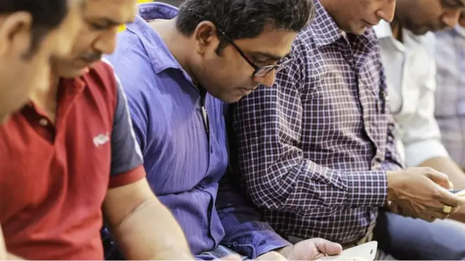 Hombres sentados concentrados en ver sus teléfonos