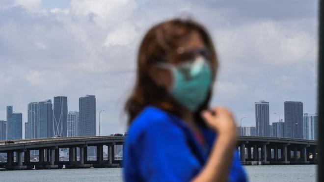 A health care worker stand by the bay to watch the Wingfoot Two aircraft fly over the Mount Sinai Medical Center in Miami, on May 22, 2020