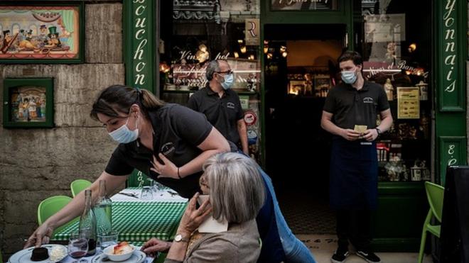 A waiter serves a client at a restaurant in Lyon in June