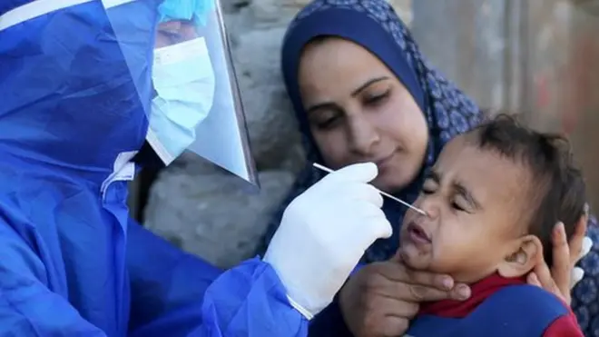 عامل طبي فلسطيني يجري اختبار الكشف عن فيروس كورونا لطفل