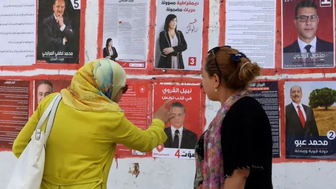 امرأتان أمام ملصقات دعائية للمرشحين