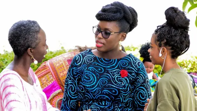 Liliane Coulibaly, propriétaire d'un salon de coiffure pour cheveux naturels (au centre) discutant avec une femme et une jeune fille lors du Dakar Hair Day.