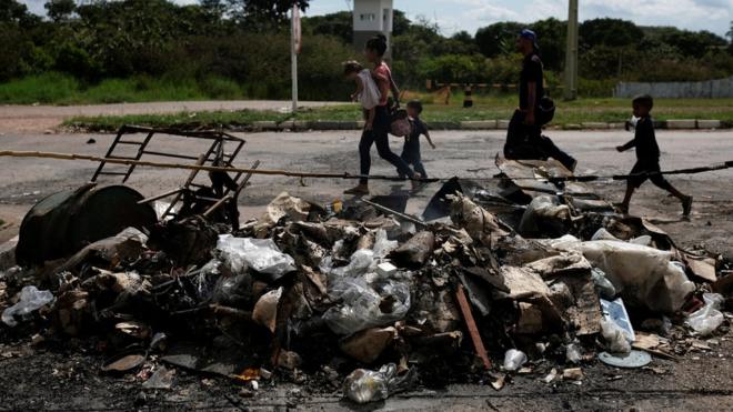 Venezuelanos diante de tendas queimadas em protesto no sábado