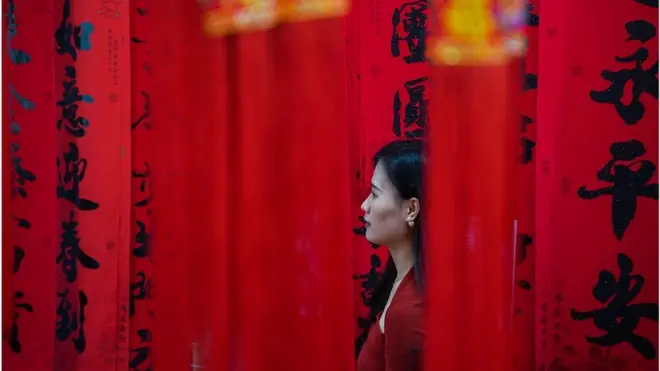 廣西南寧一名婦女在即將到來的中國農曆新年前購買紅燈籠和對聯裝飾。