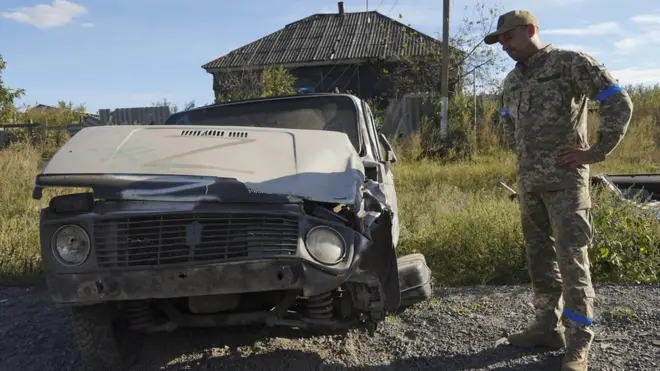 A Ukrainian soldier beside a Russian vehicle, with the Z marking, in the Kharkiv region on Friday