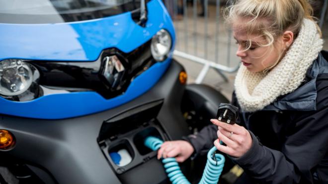 A woman charges an electric vehicle