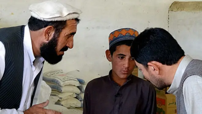 حاجی غالب (سمت چپ) و سید انور خبرنگار بی‌بی‌سی در حال صحبت با پسری که پدرش توسط افراد داعش کشته شده است.