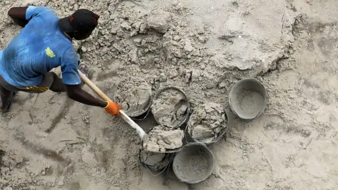 Un homme qui ramasse du sable